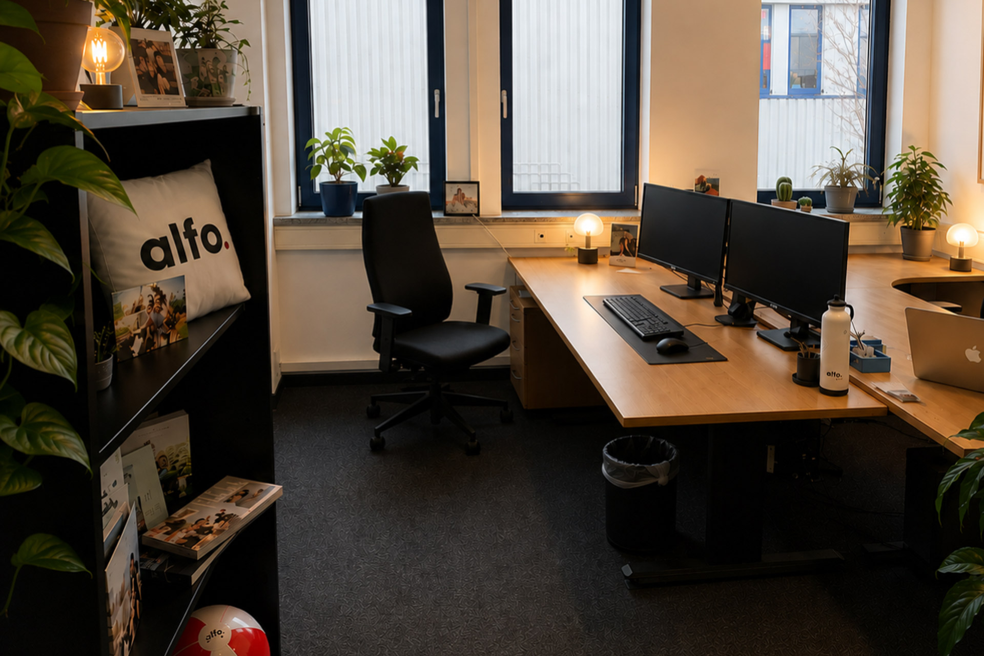 Moderner Arbeitsplatz im RINGFOTO Büro mit Schreibtisch, zwei Monitoren, Pflanzen und persönlicher Arbeitsplatzgestaltung.